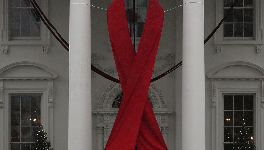 A red ribbon is displayed on the North Portico of the White House to recognize World AIDS Day, December 1, 2015. Photo by Getty Images