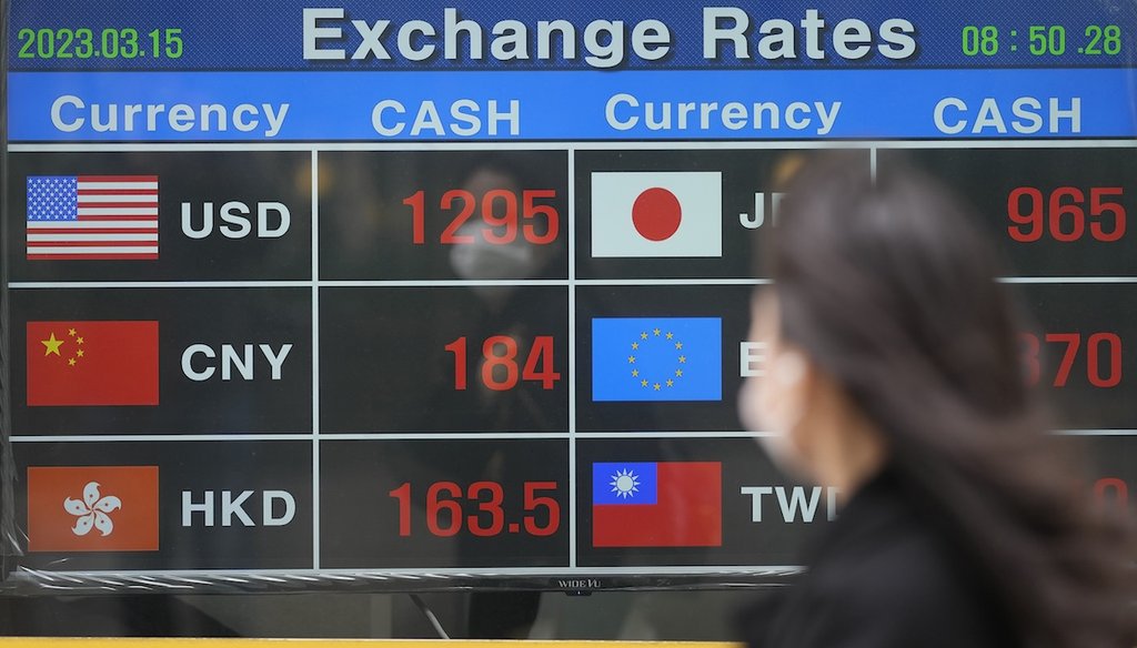 A woman passes an electronic foreign currency exchange rates in Seoul, South Korea, on March 15, 2023. (AP)