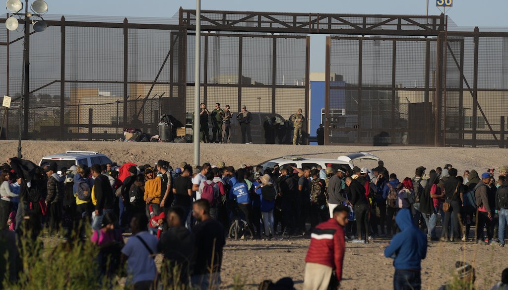 Un grupo de migrantes espera en el lado de Estados Unidos de la frontera en frente de una puerta vigilada por autoridades estadounidenses después de cruzar del lado mexicano en Ciudad Juárez, el 29 de marzo de 2023. (AP)