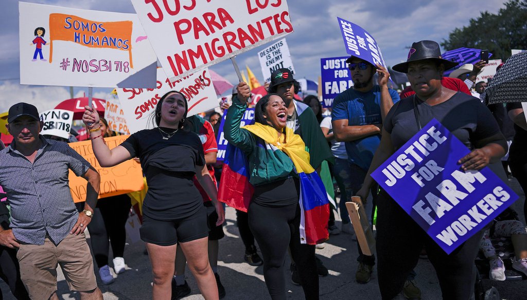 People carry signs that read in Spanish, "Justice for Immigrants" and "We are humans" as hundreds gather to protest peacefully against Florida Senate bill 1718, June 1, 2023, in Immokalee, Fla. (AP)