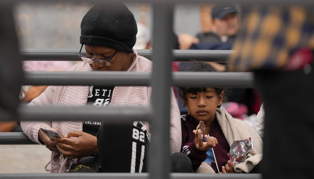 Una mujer revisa su celular mientras espera con otros para pedir asilo cerca a la puerta de entrada de San Isidro, que junta Tijuana, México con San Diego el 1 de junio de 2023 en Tijuana, México. (AP)