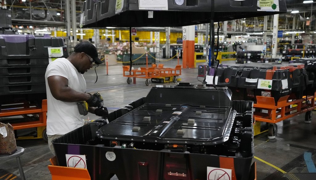 An assembly line worker uncrates an LG battery at a General Motors facility in Lake Orion, Mich., in 2023. (AP)