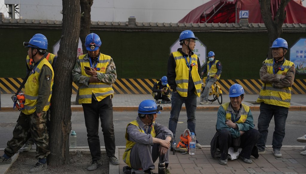 Workers wait for their ride outside a construction site in Beijing on April 9, 2024. (AP)