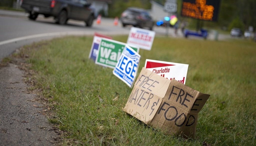 A makeshift cardboard sign leans up against campaign posters near a relief center on Oct. 3, 2024, in Vilas, North Carolina, in the aftermath of Hurricane Helene. (AP)