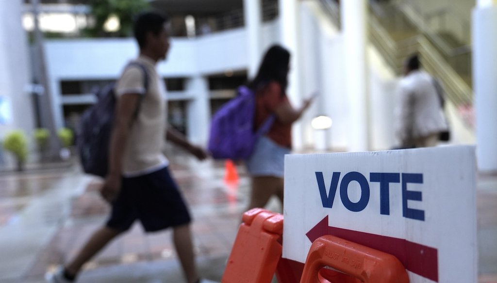 People walk past a Vote sign on the first day of early voting in the general election, Oct. 21, 2024, in Miami. (AP)