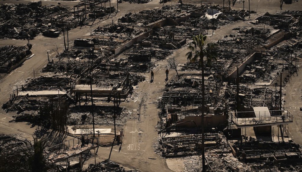 Dos personas caminan por una carretera en una comunidad devastada después del incendio Palisades en el vecindario Pacific Palisades de Los Ángeles, el 13 de enero de 2025. (AP)