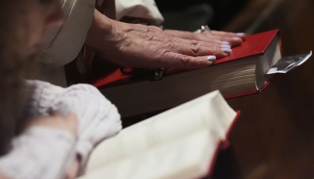 A woman touches a bible as she prays during a Mass at Holy Name Cathedral in Chicago, May 11, 2025. (AP)