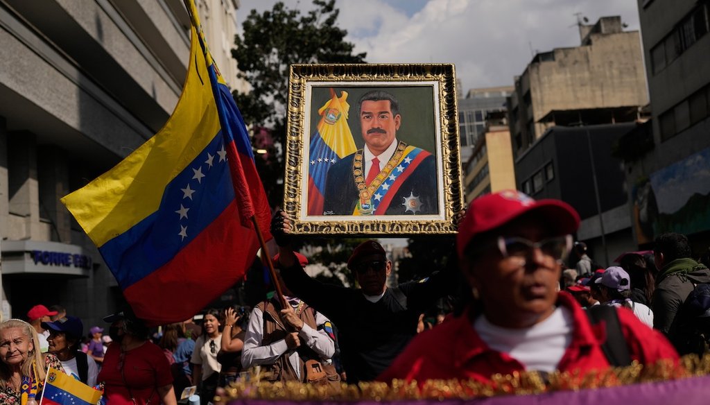 A government supporter holds an image of Nicolas Maduro during a women's march in Caracas, Venezuela, to demand his return on Jan. 6, 2026. (AP)