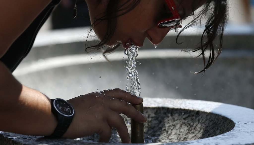 A woman drinks from a drinking fountain in Green Park in London, Thursday, July 18, 2013. (AP)
