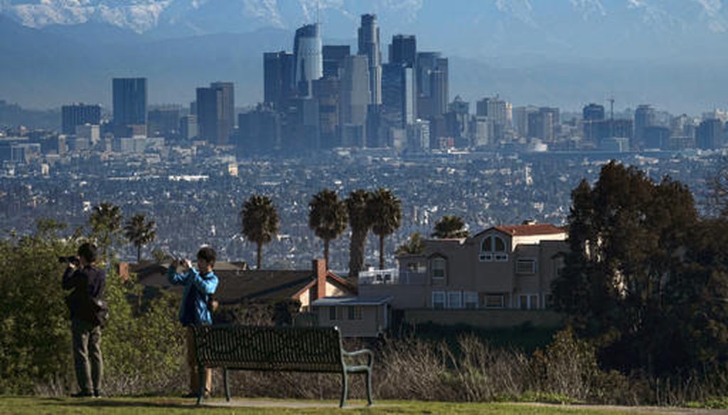 Tourists take photographs as snow covered mountain tops rise behind downtown Los Angeles from Kenneth Hahn State Recreation Area in Los Angeles on Jan. 25, 2017. (AP/Vogel)