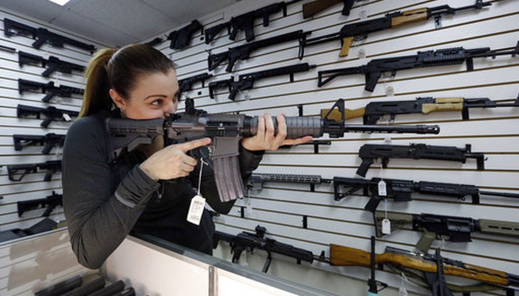 Gun shop owner Tiffany Teasdale-Causer points a Ruger AR-15 semi-automatic rifle in Lynnwood, Wash. (AP Photo/Elaine Thompson)