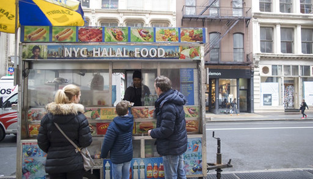 In this Wednesday, April 4, 2018 photo, a family buys hot dogs from a street vendor on Broadway in the Soho neighborhood of New York. (AP Photo/Mary Altaffer)