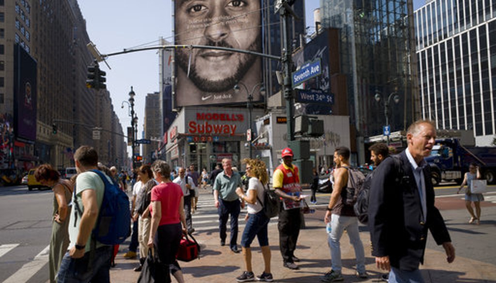 People walk by a Nike advertisement featuring Colin Kaepernick on display, Thursday, Sept. 6, 2018 in New York. (AP Photo/Mark Lennihan)