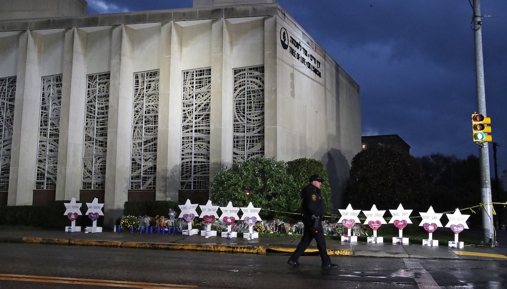 A Pittsburgh Police officer walks past the Tree of Life Synagogue and a memorial of flowers and stars in Pittsburgh on Oct. 28, 2018. (AP)