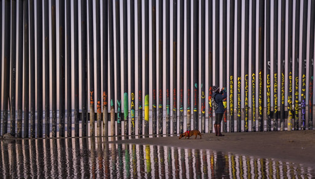 A woman takes a snapshot by the border fence between San Diego, Calif., and Tijuana, as seen from Mexico, on Jan. 3, 2019. (AP/Daniel Ochoa de Olza)