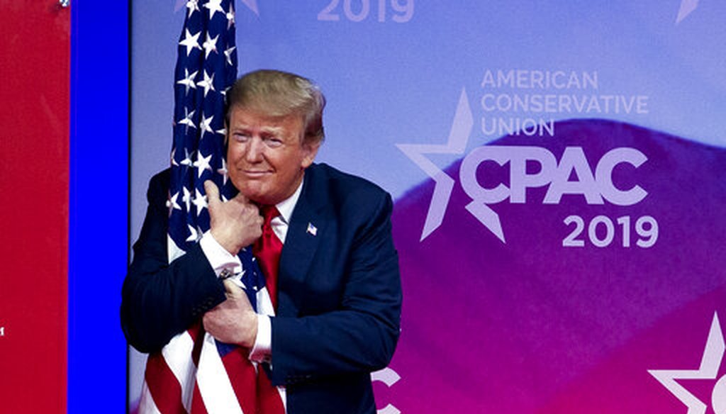 President Donald Trump hugs the American flag as he arrives to speak at Conservative Political Action Conference on March 2, 2019. (AP)