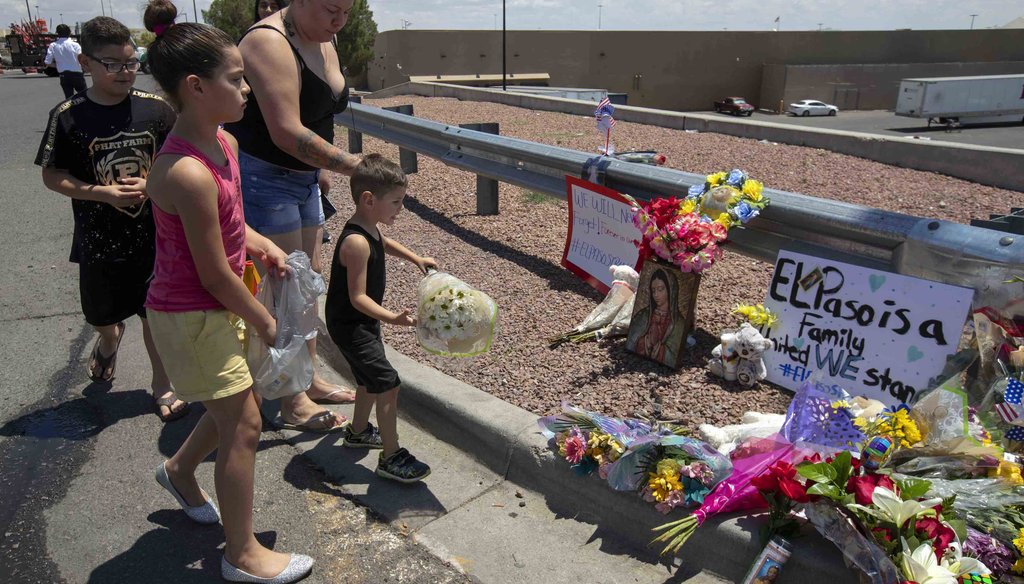 An El Paso family bring flowers to the makeshift memorial for the victims of Saturday mass shooting at a shopping complex in El Paso, Texas, Sunday, August 4, 2019. (AP Photo/Andres Leighton)