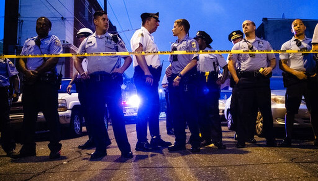 Officers gather for crowd control near a massive police presence set up outside a house as they investigate a shooting in Philadelphia, Wednesday, Aug. 14, 2019. (AP Photo/Matt Rourke)