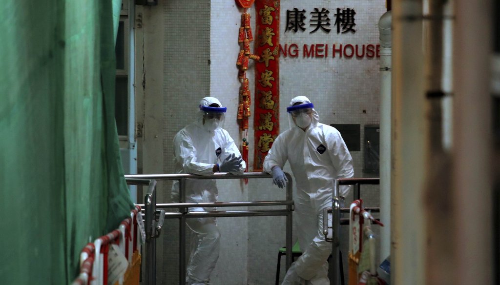 Personnels wearing protective suits wait near an entrance at the Cheung Hong Estate, a public housing estate during evacuation of residents in Hong Kong on Feb. 11, 2020. (AP)