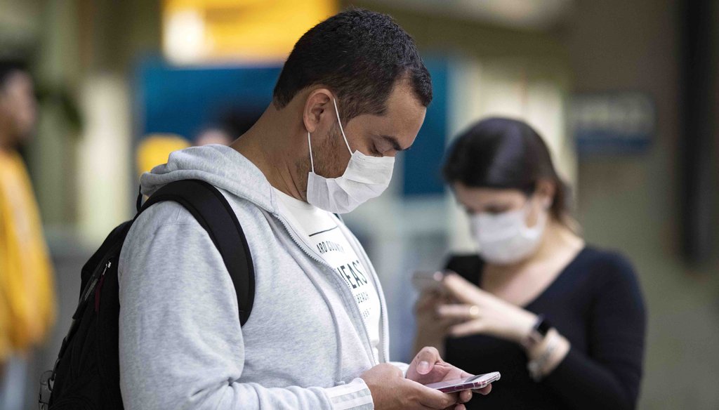 Passengers wearing masks as a precaution against the spread of the new coronavirus COVID-19 use their phones at the Sao Paulo International Airport in Sao Paulo, Brazil, on Feb. 27, 2020. (AP)