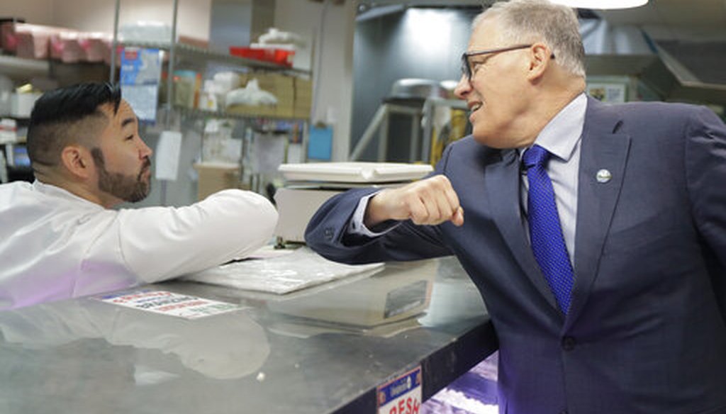 Washington Gov. Jay Inslee, right, greets a worker at the seafood counter of the Uwajimaya Asian Food and Gift Market on March 3, 2020. (AP)