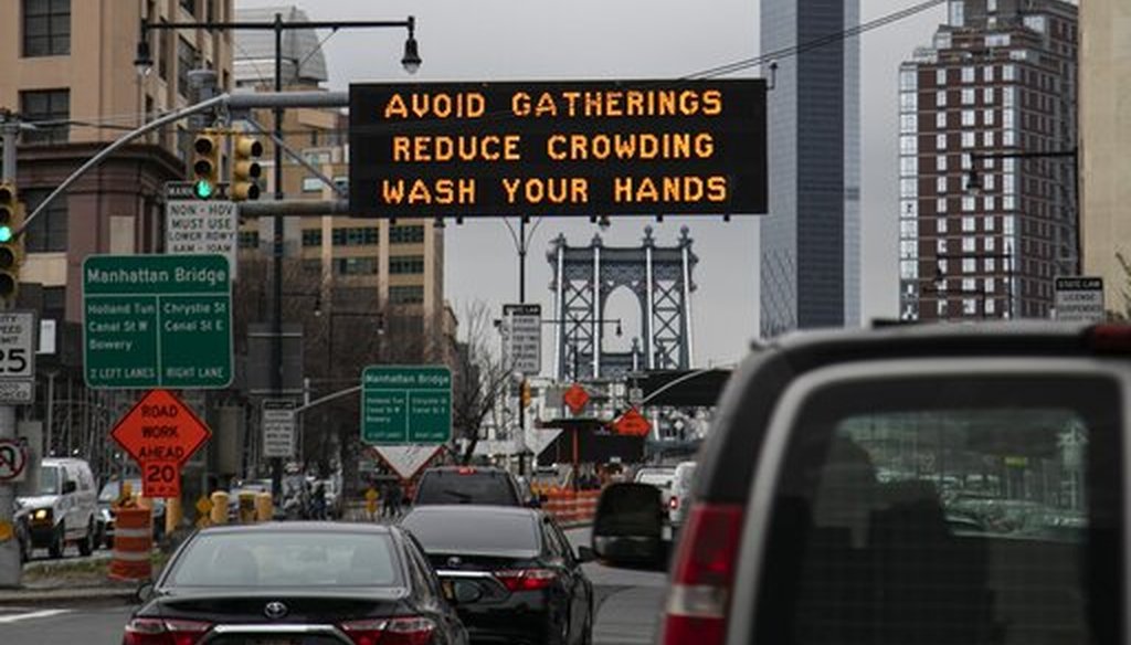The Manhattan bridge is seen in the background of a flashing sign urging commuters to avoid gatherings, reduce crowding and to wash hands in the Brooklyn borough of New York, March 19, 2020. (AP/Wong Maye-E)