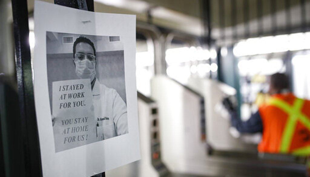 A flier urging customers to remain home hangs at a turnstile as an MTA employee sanitizes surfaces at a subway station on March 20, 2020, in New York City. (AP)
