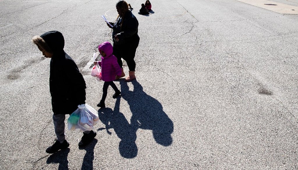 A woman and children walk away from the John H. Webster Elementary School carrying donated food and educational materials, in Philadelphia, Thursday, March 26, 2020. (AP)