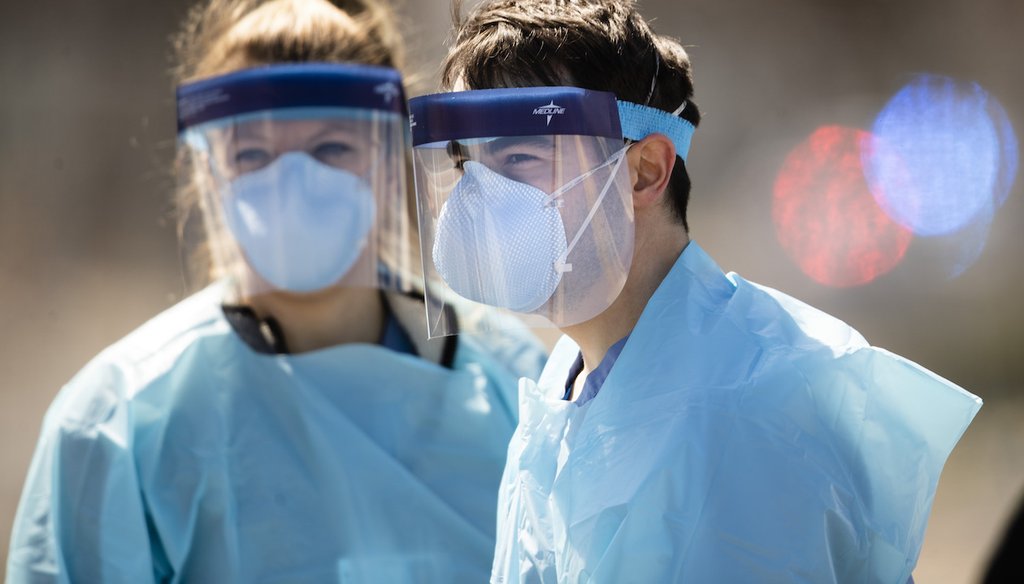 Medical workers in protective masks wait to administer COVID-19 tests at a facility in Camden, N.J. (Associated Press)