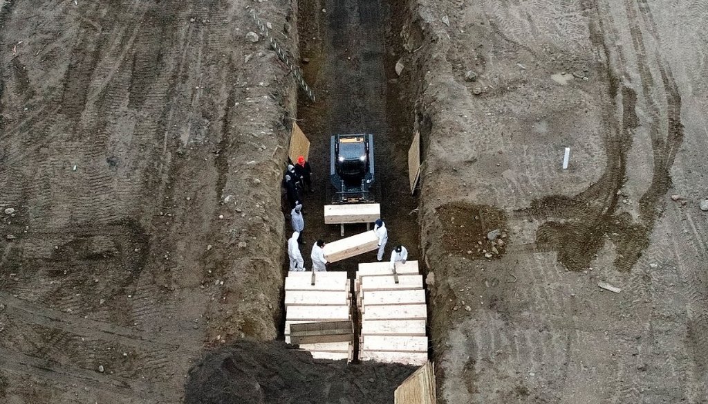 Workers wearing personal protective equipment bury bodies in a trench on Hart Island, Thursday, April 9, 2020, in the Bronx borough of New York.  (AP)