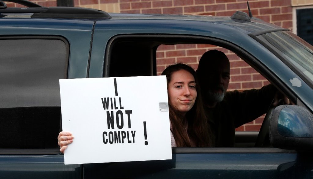 A passenger in a vehicle holds a sign during a protest at the State Capitol in Lansing, Mich., Wednesday, April 15, 2020. (AP)
