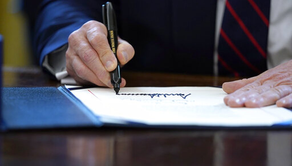 In this March 27, 2020 file photo, President Donald Trump signs the coronavirus stimulus relief package in the Oval Office at the White House in Washington. (AP/Evan Vucci)