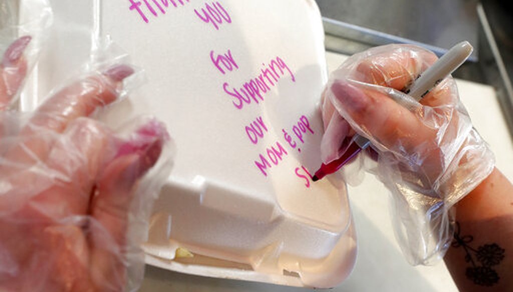 Jaime Chase writes a personal note thanking customers on a carry out lunch box at Chase's Diner Thursday, April 23, 2020, in Chandler, Ariz. (AP/Matt York)