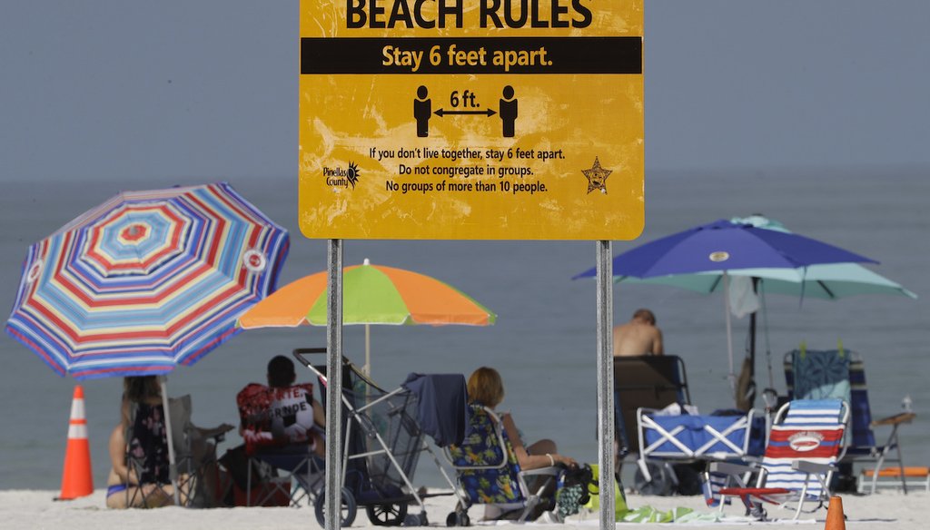 Beachgoers sunbathe near a beach rules sign after Clearwater Beach officially reopened to the public Monday, May 4, 2020. (AP)