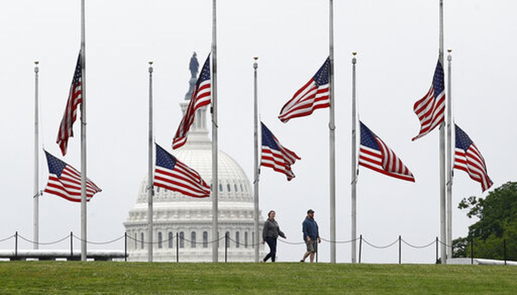 On May 22, 2020, walkers pass American flags flying at half-staff at the Washington Monument in Washington. (AP/Semansky)