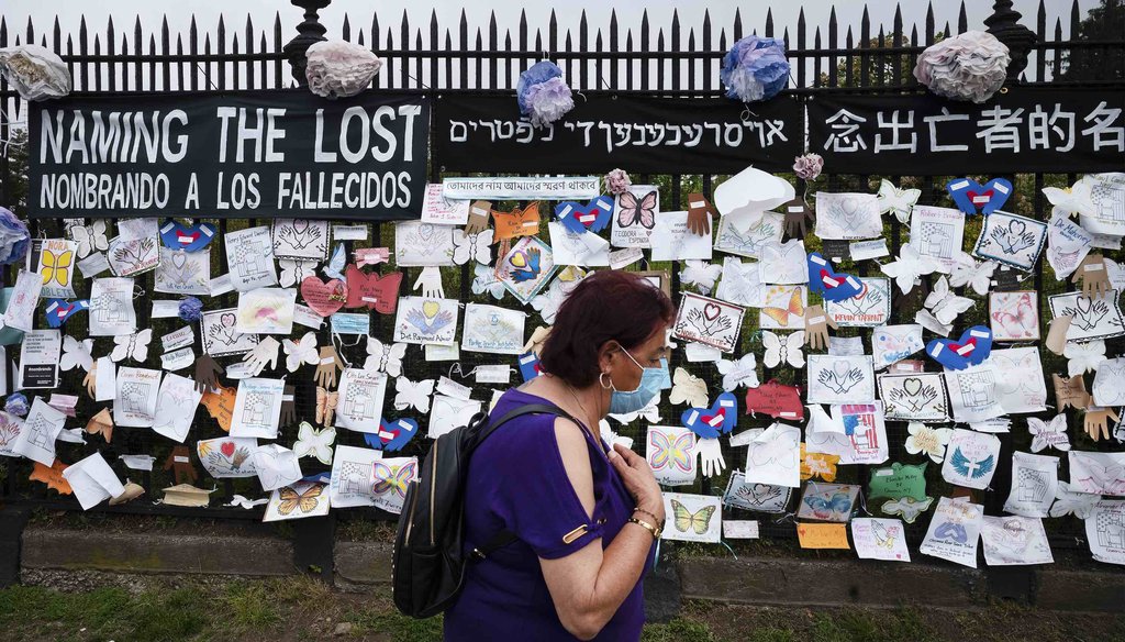 A woman passes a fence outside Brooklyn's Green-Wood Cemetery adorned with tributes to victims of COVID-19 on May 28, 2020, in New York. (AP)