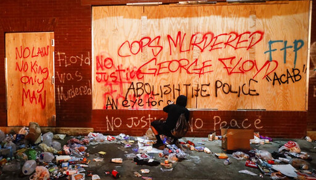 A protester sprays graffiti on a wall near the Minneapolis 3rd Police Precinct on May 28, 2020, in Minneapolis. (AP/Minchillo)