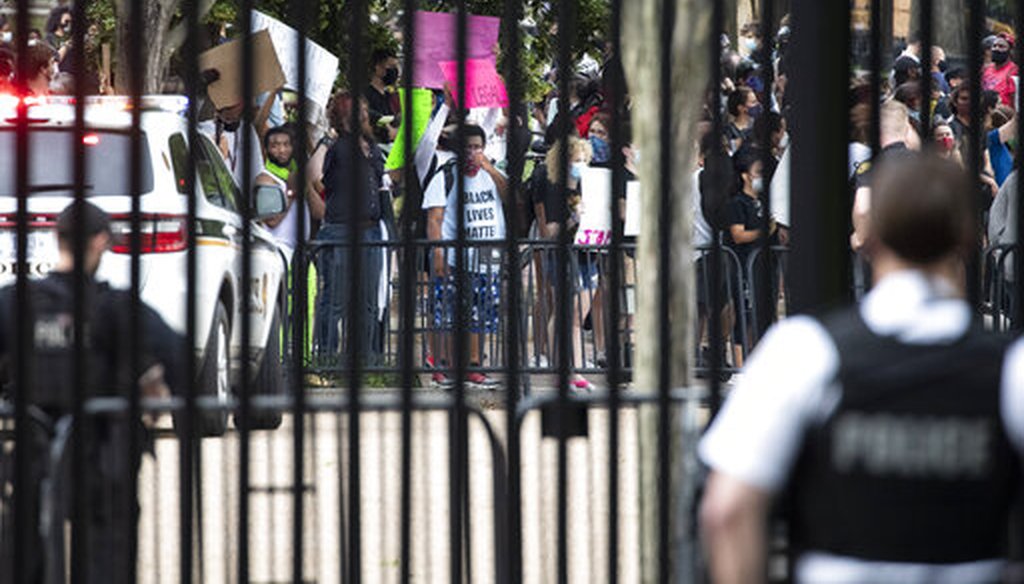 A U.S. Secret Service officer stands inside the fence at the White House as demonstrators protest the death of George Floyd on May 29, 2020, in Washington. (AP/Brandon)