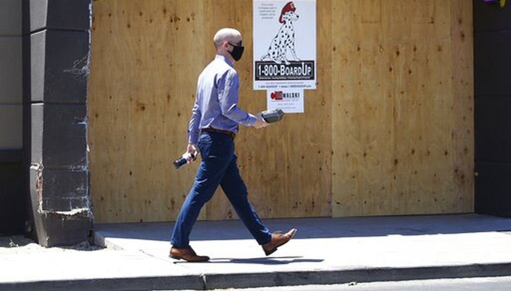 A pedestrian with a takeout lunch in hand walks through an area of Scottsdale, Ariz., known for busy restaurants, bars and nightlife, June 30, 2020. (AP/Ross D. Franklin)