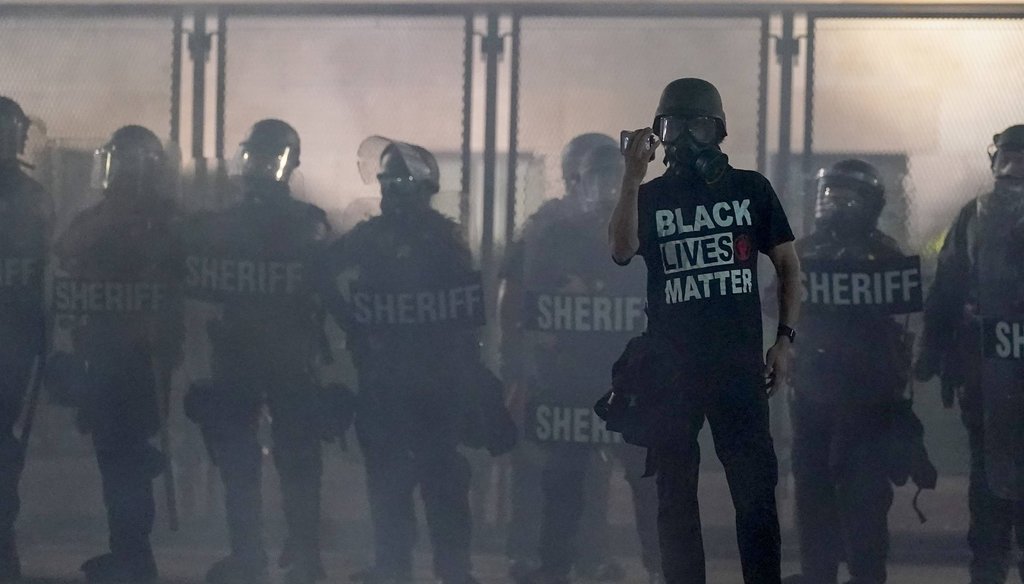 A protester holds up a phone as he stands in front of authorities on Aug. 25, 2020, in Kenosha, Wis. (AP)