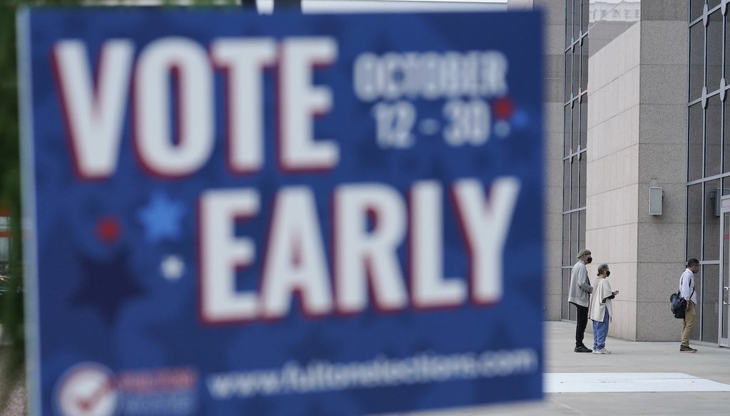 Behind a sign listing early voting dates for Fulton County, Georgia, a line forms outside of the State Farm Arena for early voting on Oct. 12, 2020, in Atlanta. (AP/Anderson)