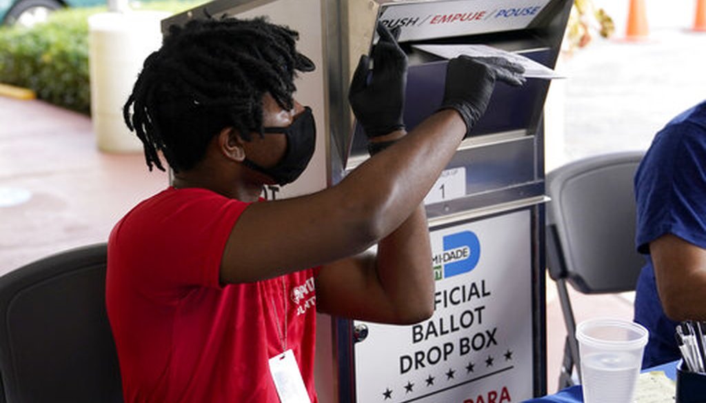 Election worker Najeh Fisher places a vote-by-mail ballot for the Nov. 3 general election into an official ballot drop box at the Miami-Dade County Elections Department, Wednesday, Oct. 14, 2020, in Doral, Fla. (AP)
