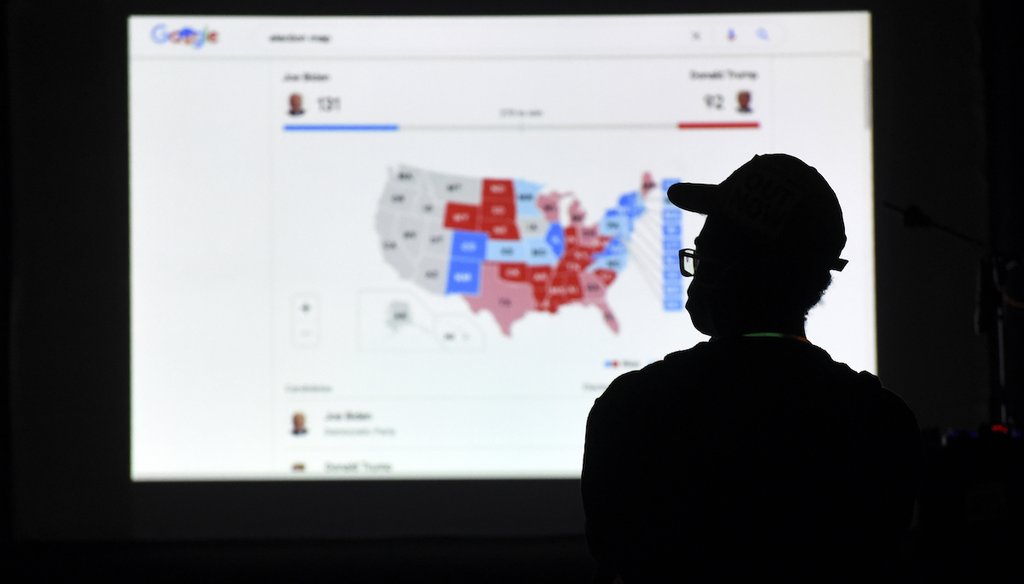 Un hombre mira los resultados en una pantalla la noche de las elecciones en Independence Mall en Filadelfia el 3 de noviembre de 2020. (AP)