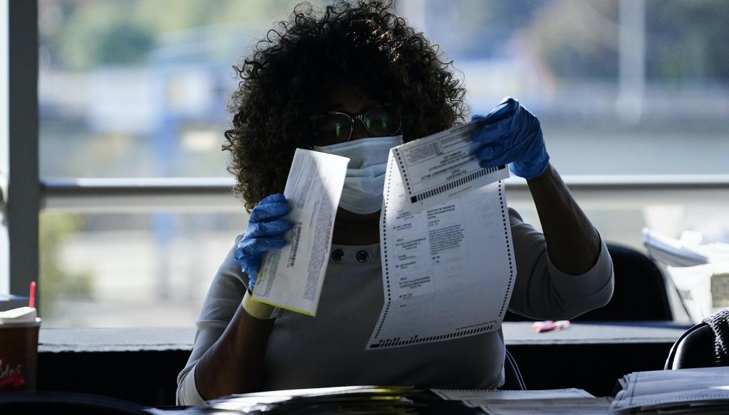 An election personnel examines a ballot as vote counting in the general election continues at State Farm Arena on Nov. 4, 2020, in Atlanta. (AP)