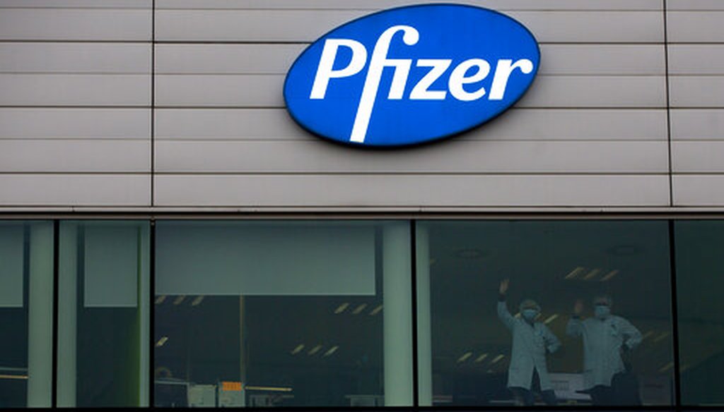Two workers wave from a window at Pfizer Manufacturing in Puurs, Belgium, on Dec. 2, 2020. (AP/Mayo)