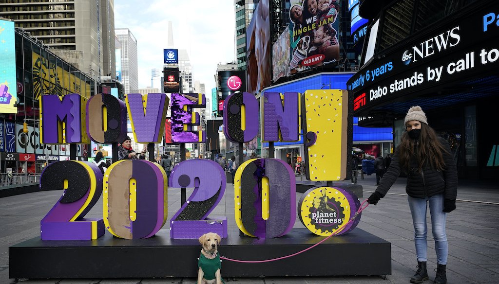 Simona Faidiga makes sure Maggie, her dog, stays in position for a picture in front of a sign that reads "Move On 2020!" In Times Square, New York, Monday, Dec. 28, 2020. (AP)