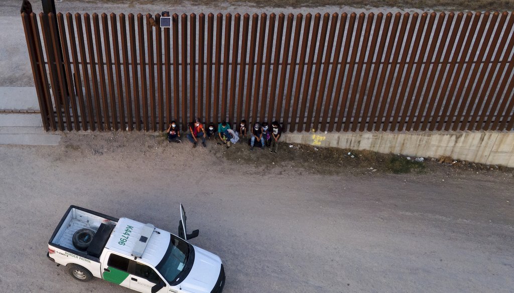 A U.S. Customs and Border Protection vehicle is seen next to migrants after they were detained and taken into custody, Sunday, March 21, 2021, in Abram-Perezville, Texas. (AP/Cortez)