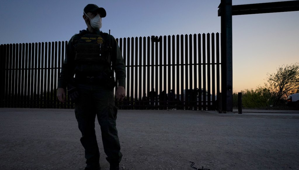 A U.S. Customs and Border Protection agent looks on near a gate on the U.S.-Mexico border wall as agents take migrants into custody, Sunday, March 21, 2021, in Abram-Perezville, Texas. (AP/Cortez)