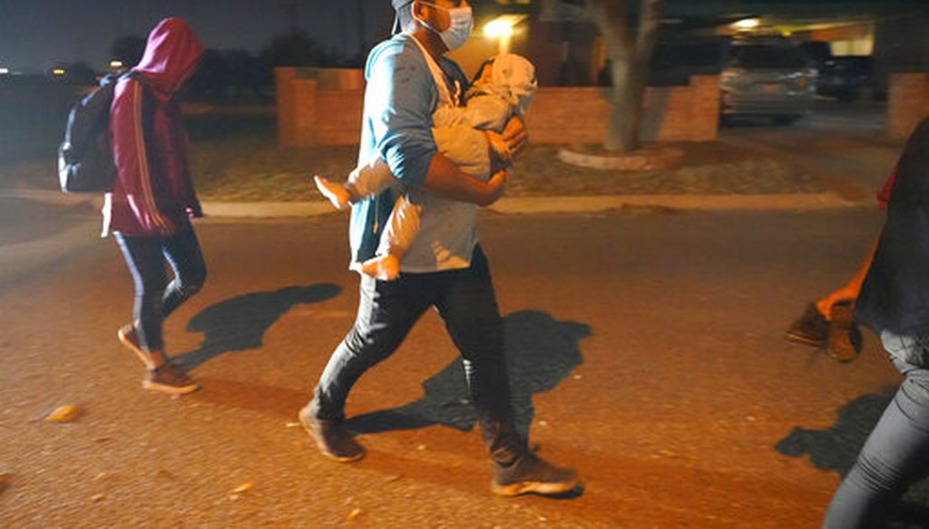 A migrant carries a child to an intake area after turning themselves in upon crossing the U.S.-Mexico border on March 24, 2021, in Roma, Texas. (AP)