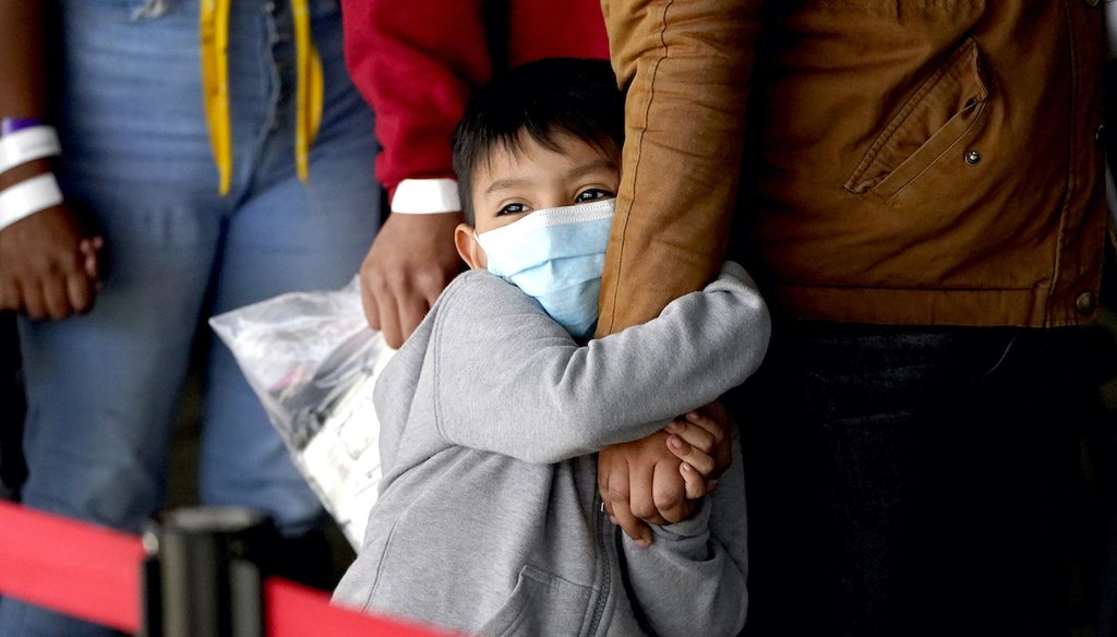 A migrant child holds onto a woman's arm as they wait to be processed by a humanitarian group after being released from U.S. Customs and Border Protection custody at a bus station, March 17, 2021, in Brownsville, Texas. (AP)